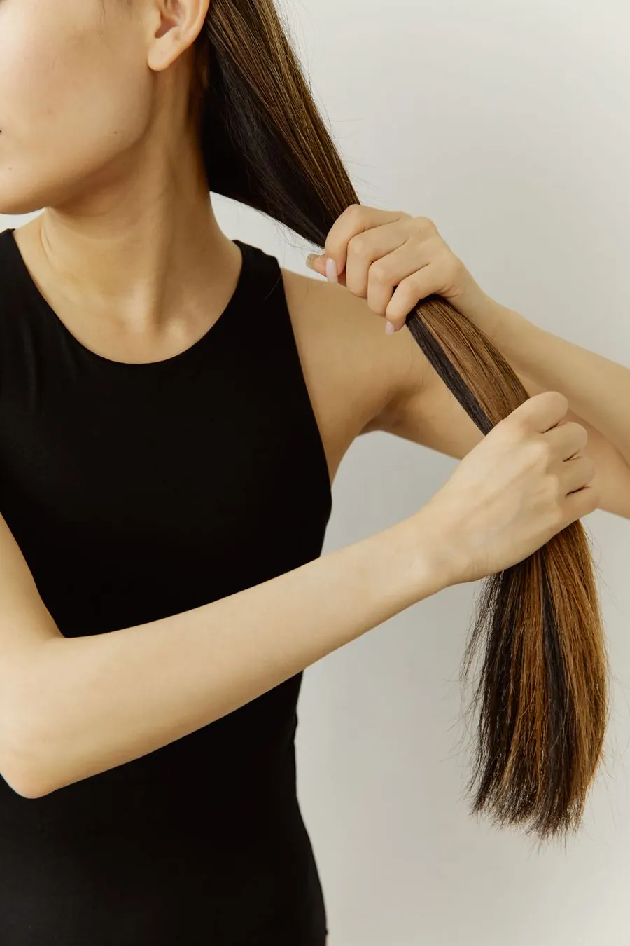Mujer sujetando su cabello castaño largo y liso