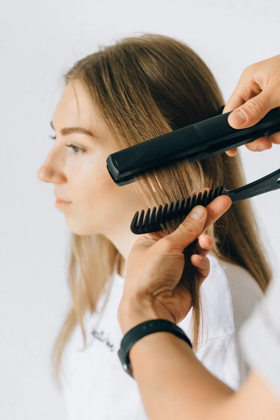 Estilista alisando el cabello de una clienta
